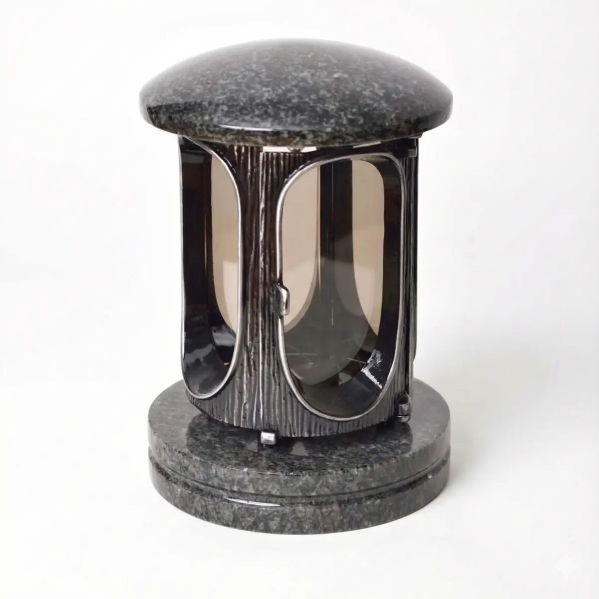 Rounded dark granite memorial lantern with curved decorative metal panels and domed lid.