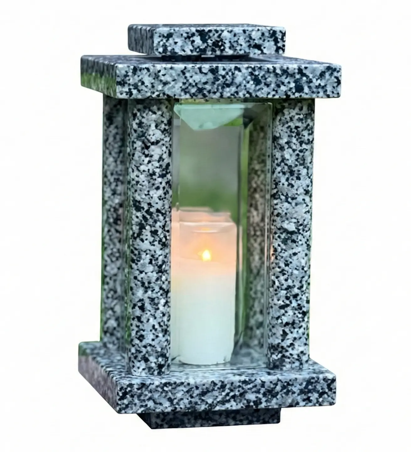 Light granite memorial lantern outdoors on a grave tablet with a candle glowing inside.